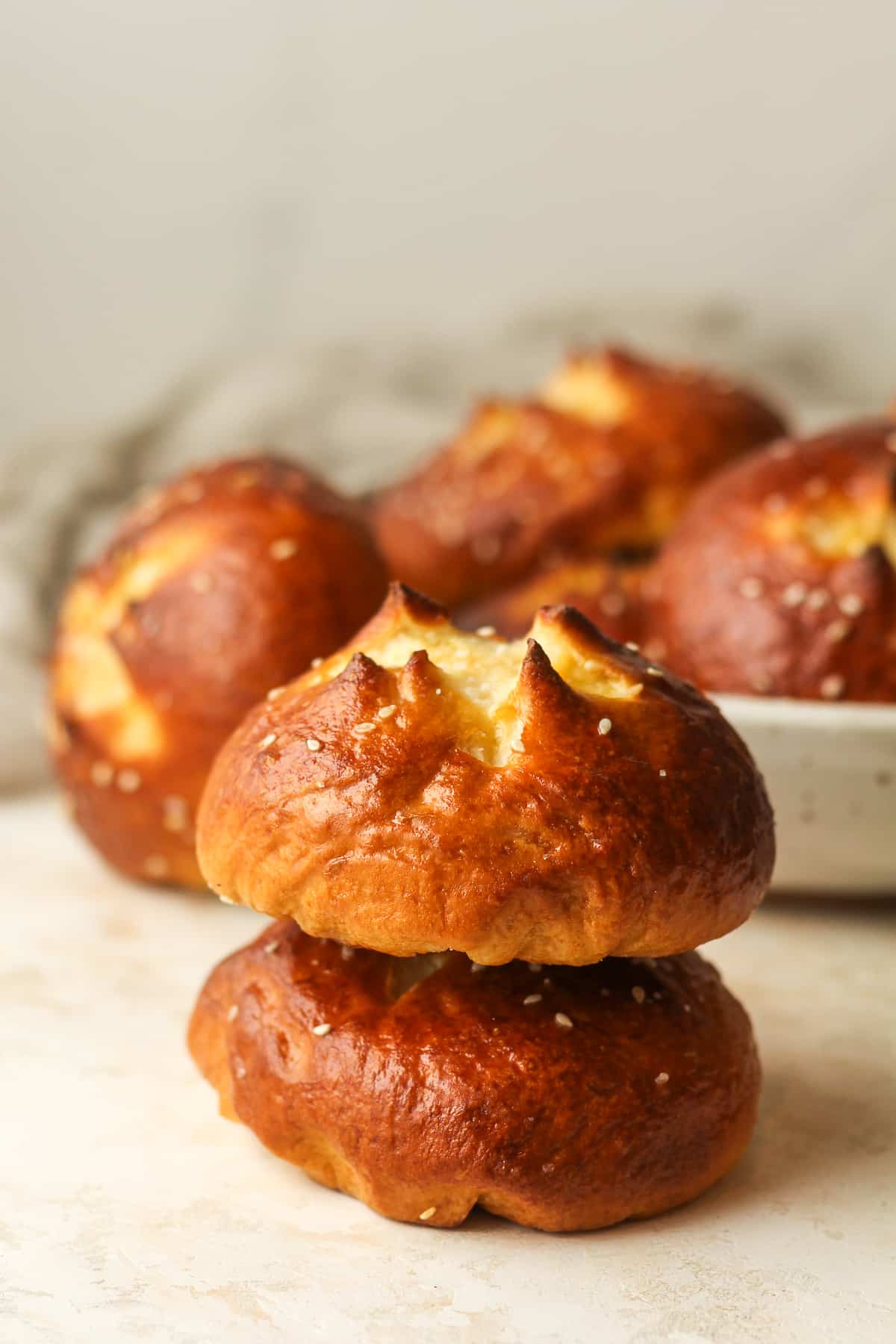 A stack of two pretzel buns in front of a bowl of buns.