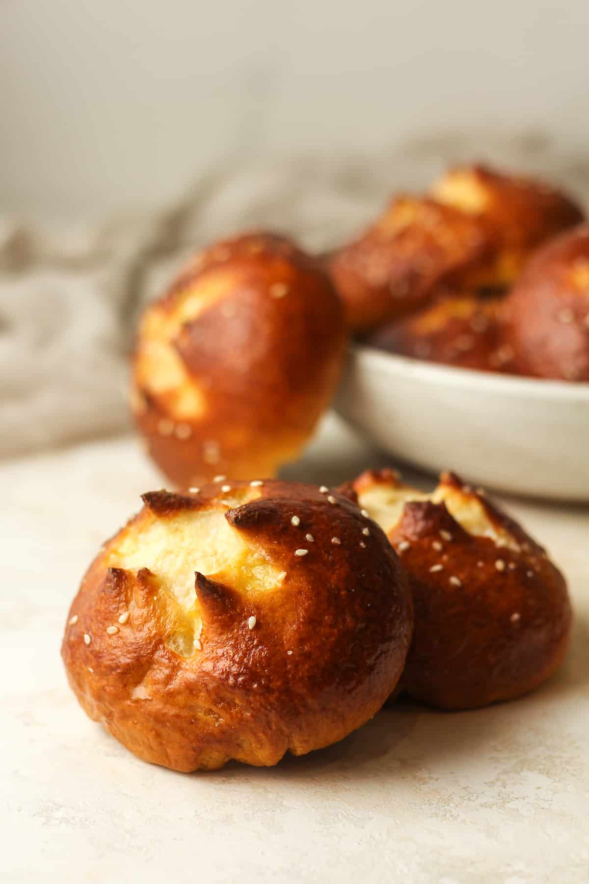 Side view of two pretzel buns with more in the background.