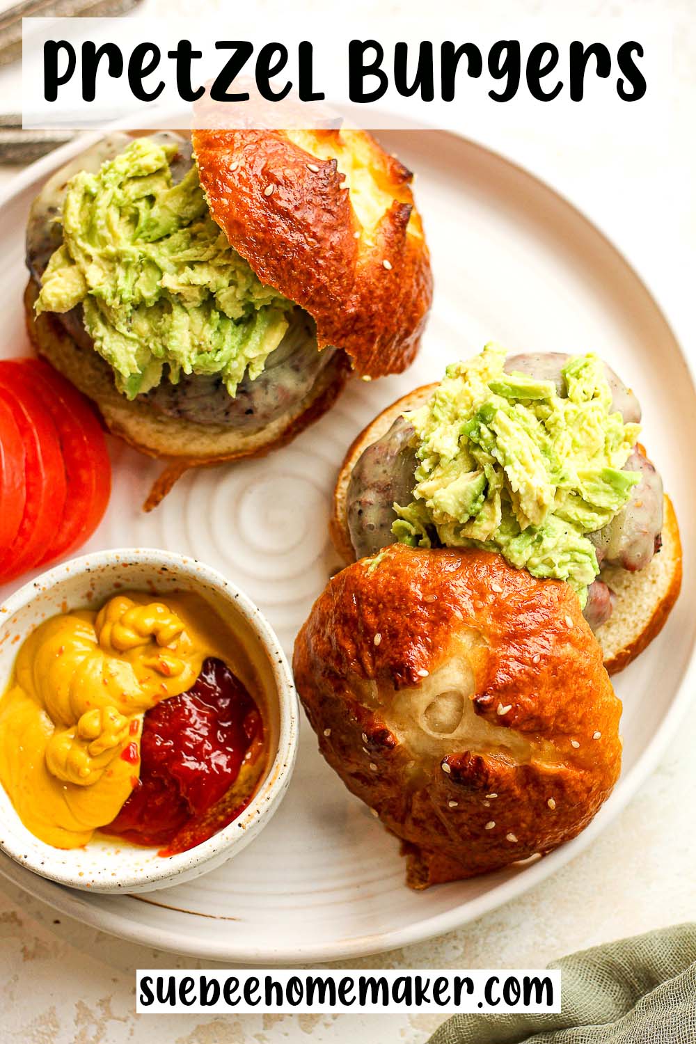 A plate of two pretzel burgers with avocado.