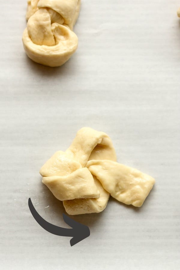 The dough showing how to twist one end (with an arrow)