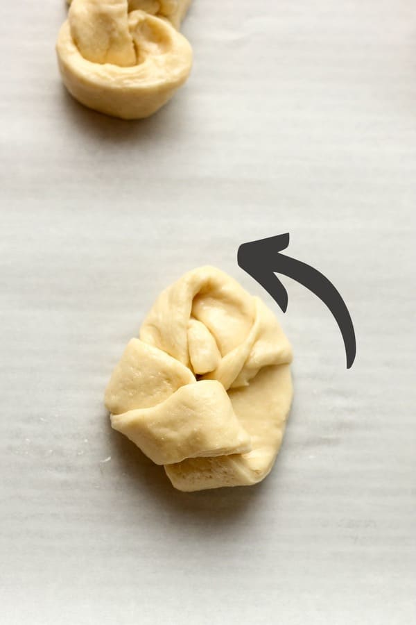 An arrow showing the other end of the dough twisted up.