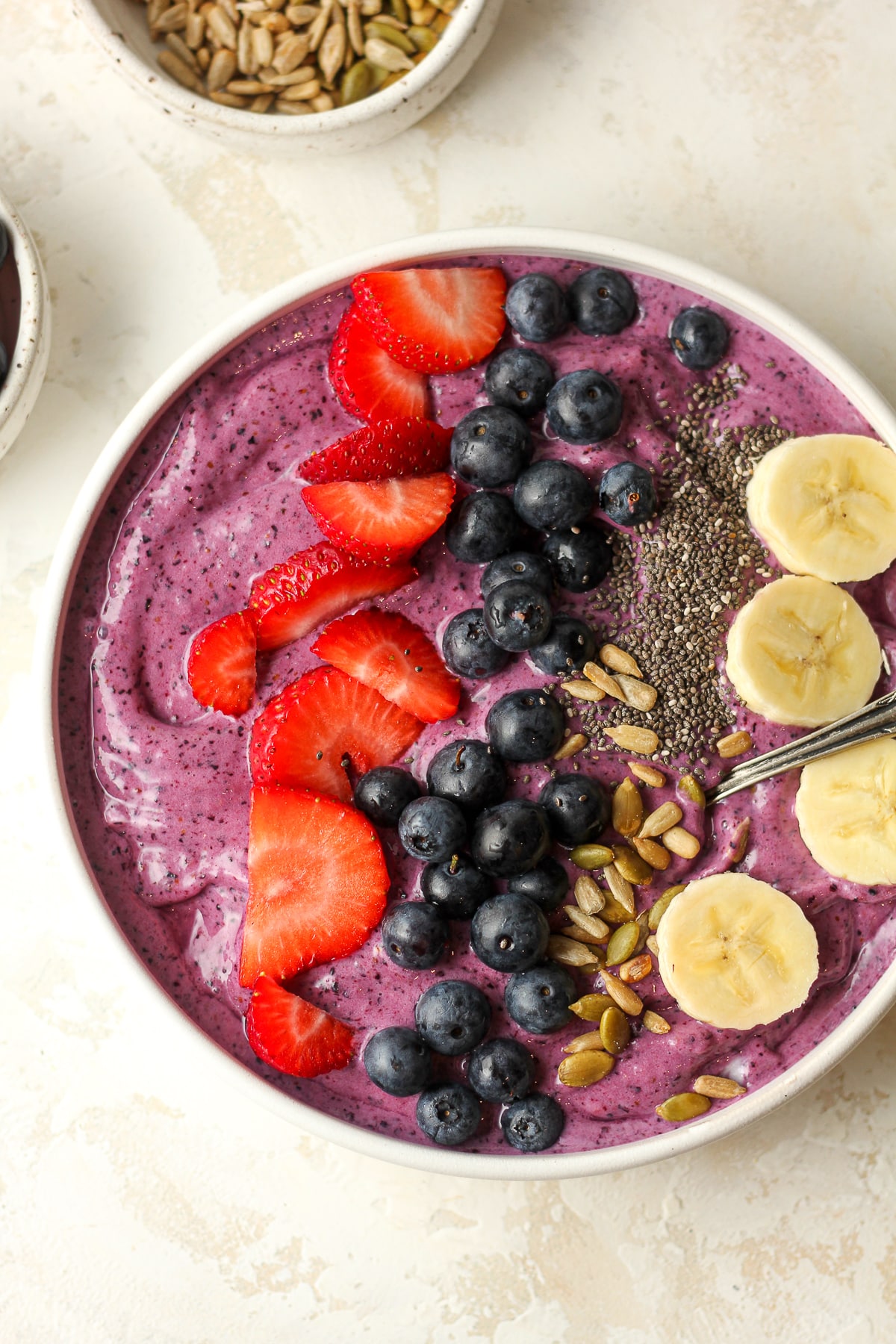Closeup on a blueberry smoothie bowl with fruit, chia seeds, and nuts.