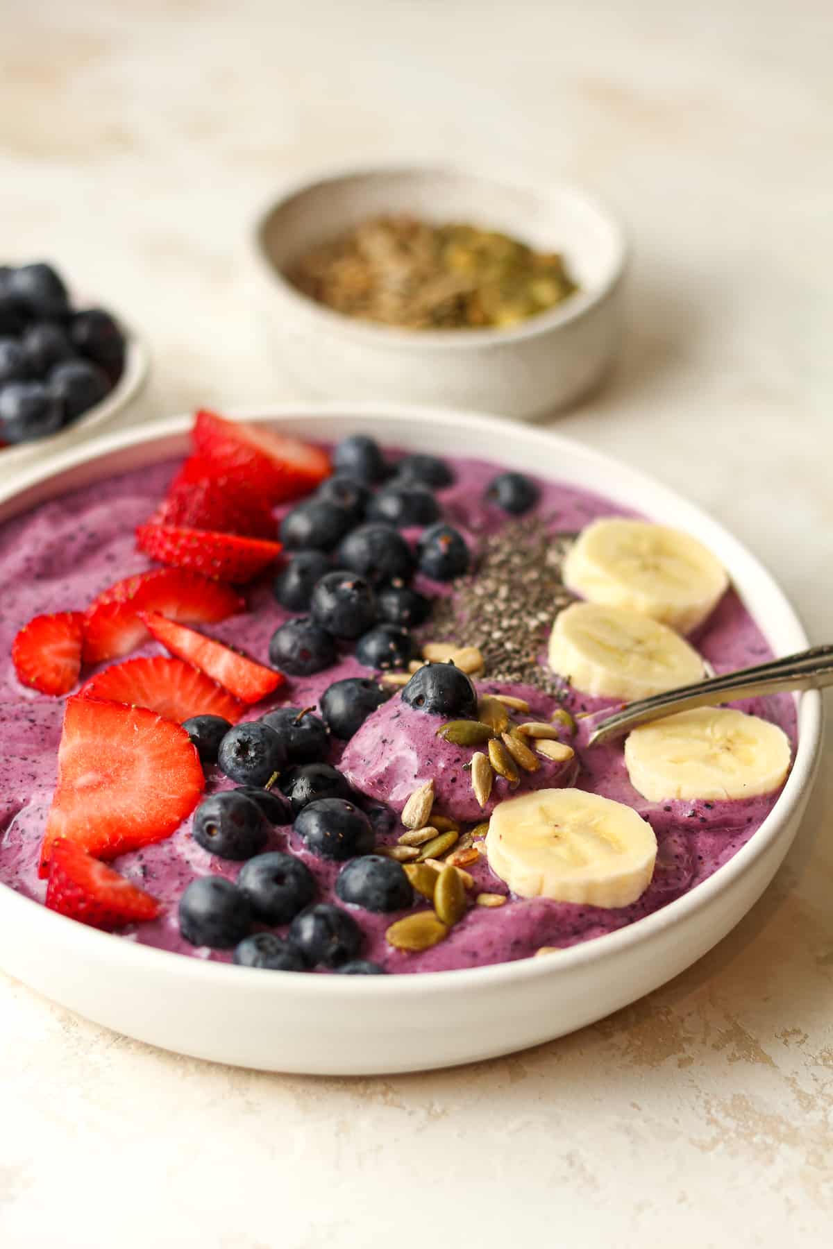 Side view of a blueberry smoothie bowl with fresh berries and banana on top.