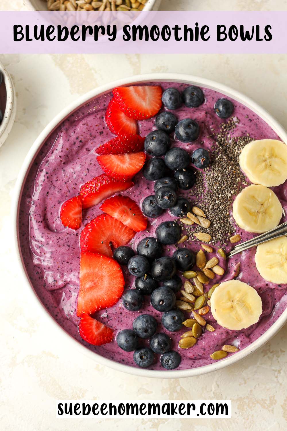 A blueberry smoothie bowl with sliced fruit and nuts.