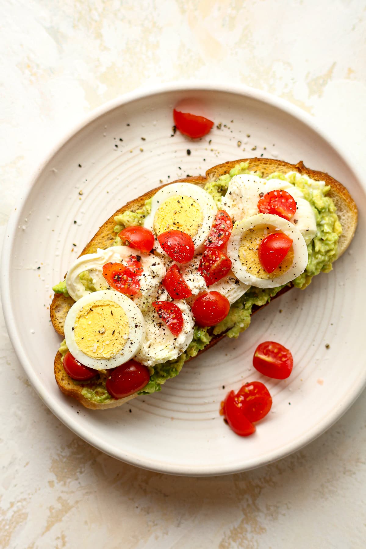 Overhead view of a plate with a slice of avocado toast with burrata.