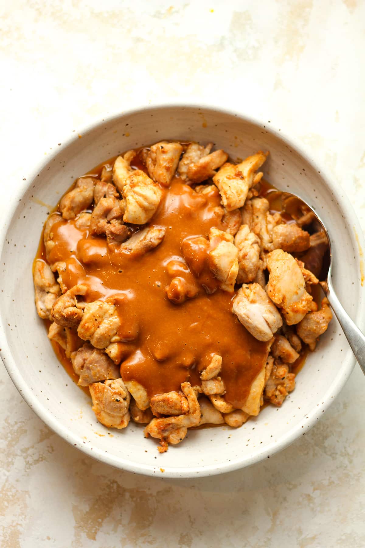 A bowl of the cooked chicken with peanut sauce on top.