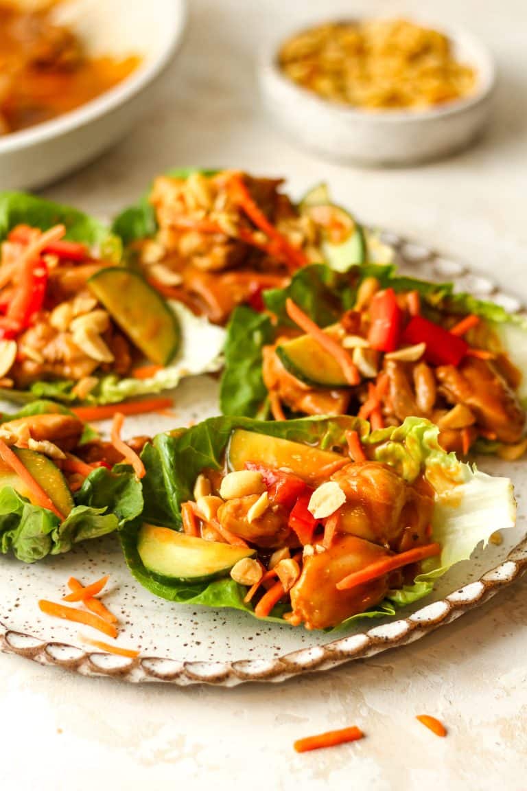 Side view of several chicken lettuce wraps with peanuts on top.