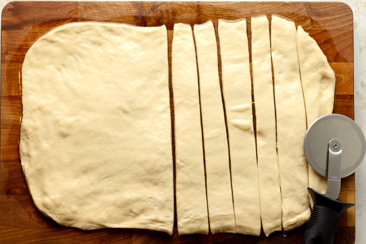 A board with some cinnamon roll dough rolled out and cut into slices.