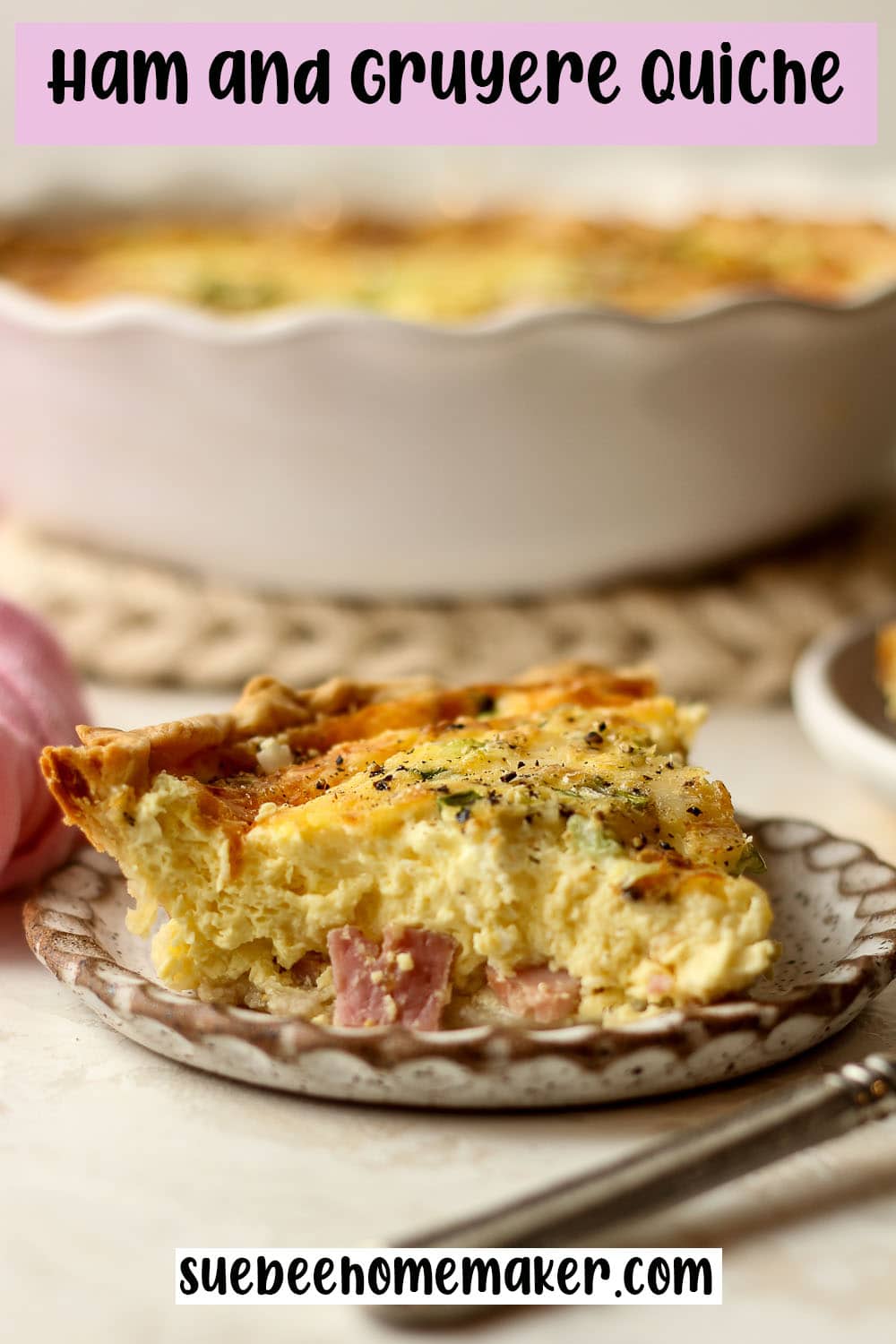 Side view of a slice of ham and gruyere quiche in front of a pie plate.