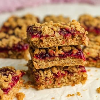 Side view of three stacked oatmeal jam bars with raspberry.