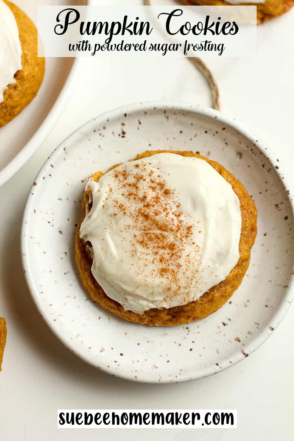 A small plate with a pumpkin cookie with powdered sugar frosting.
