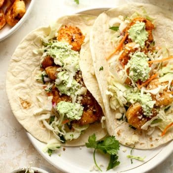 Closeup on two shrimp tacos with avocado Crema.