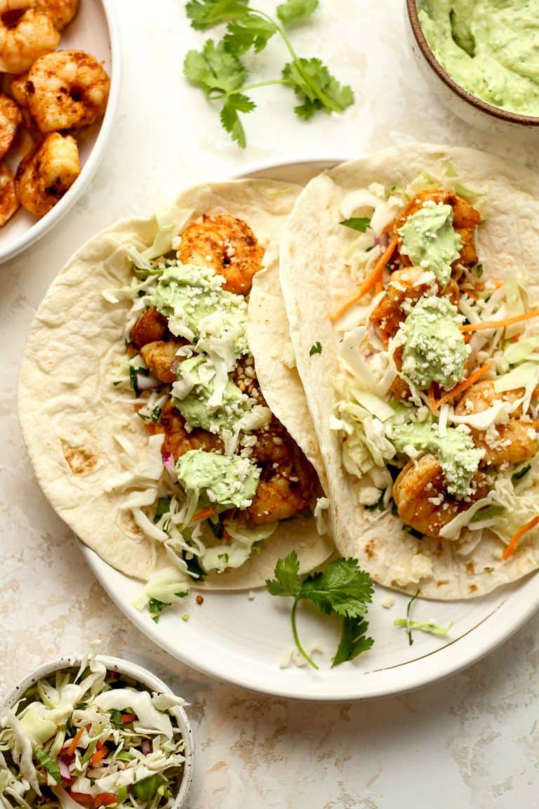 A plate of two shrimp tacos with avocado Crema.