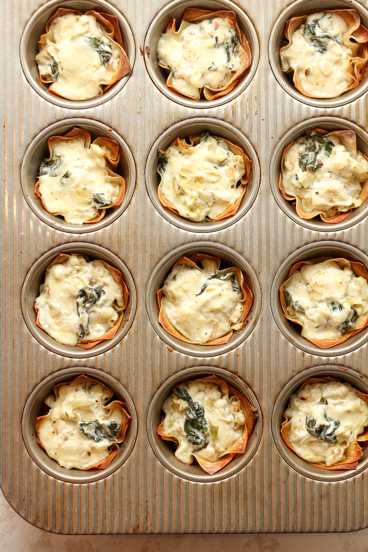 A cupcake pan of baked artichoke bites.