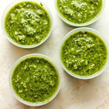 Closeup on small containers of spinach pesto.