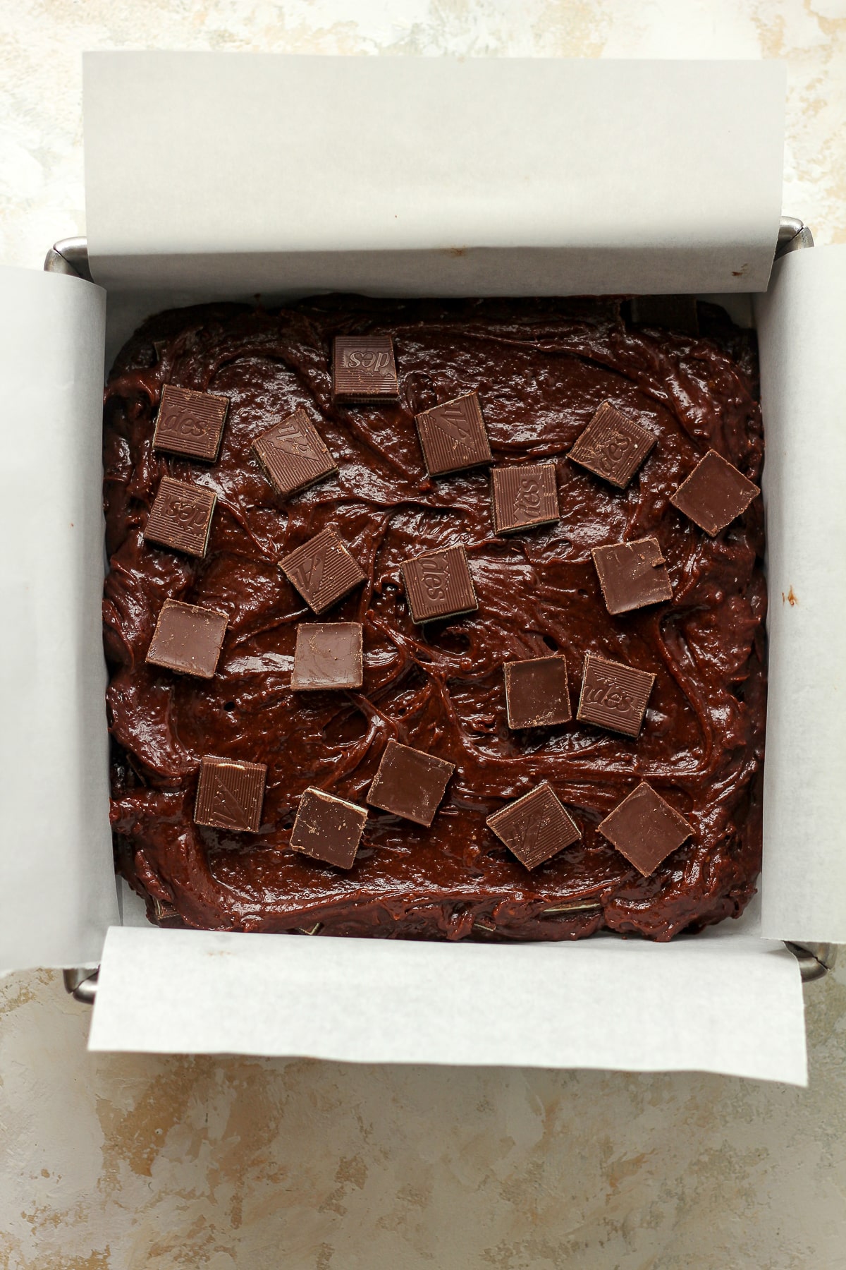 A pan of the chocolate brownies before baking with squares of mints.