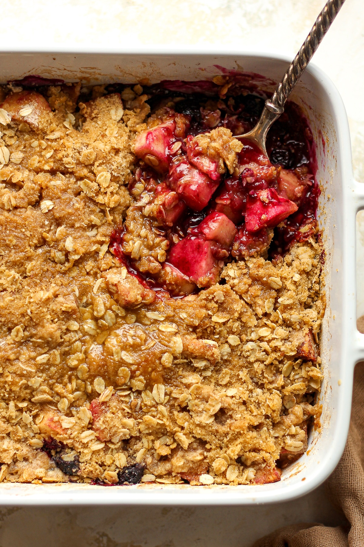 A dish of the apple blueberry crisp with a serving spoon.