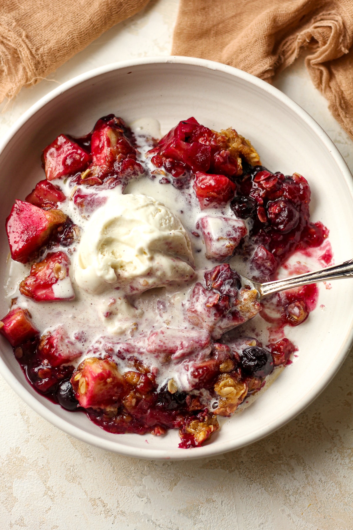 A closeup on a bowl of apple blueberry crisp.