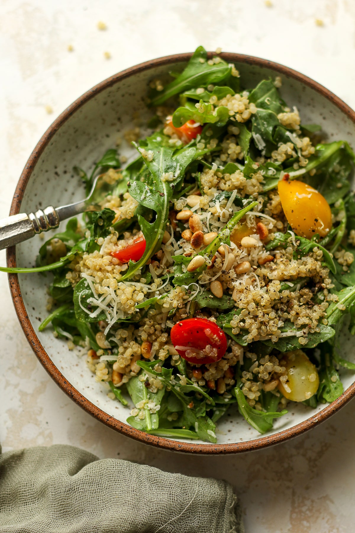 A serving of arugula quinoa salad with a fork.