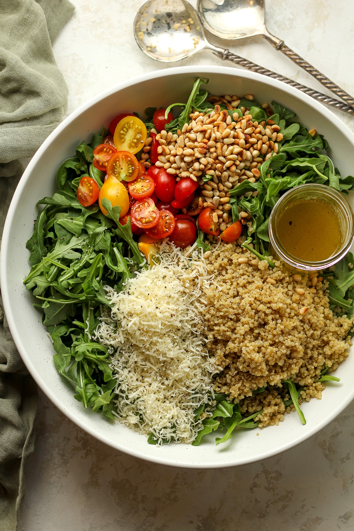 A large salad bowl with the ingredients for the arugula salad separated by ingredient.