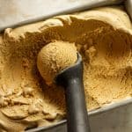 A loaf pan of butterscotch ice cream with a perfect scoop.