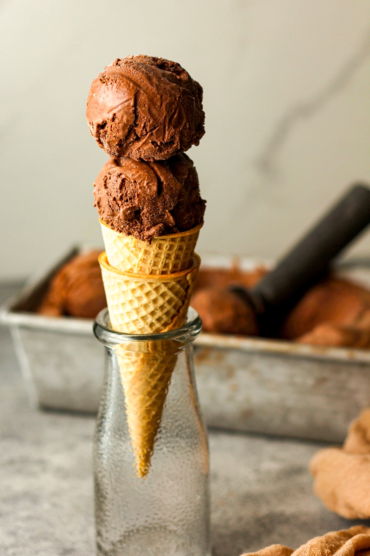 Side view of a double dip of dark chocolate ice cream with the remaining ice creaming the background.