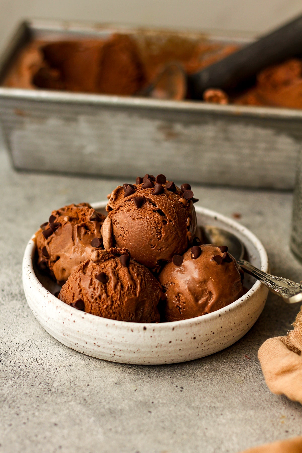 A bowl of four dips of dark chocolate ice cream with a spoon.