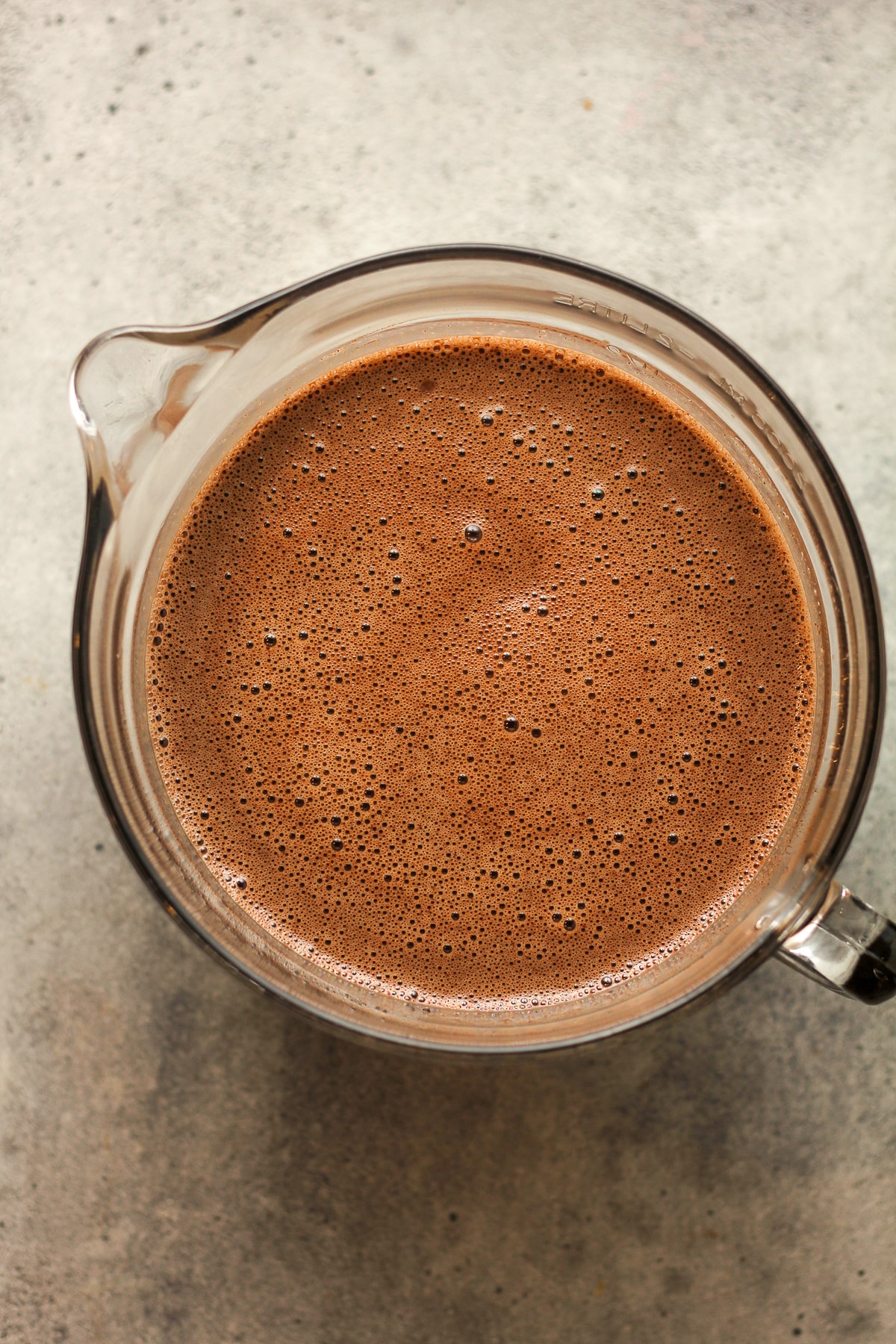 A large measuring cup of the dark chocolate ice cream liquid.