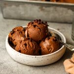 Side view of a bowl of dark chocolate ice cream with mini chocolate chips.