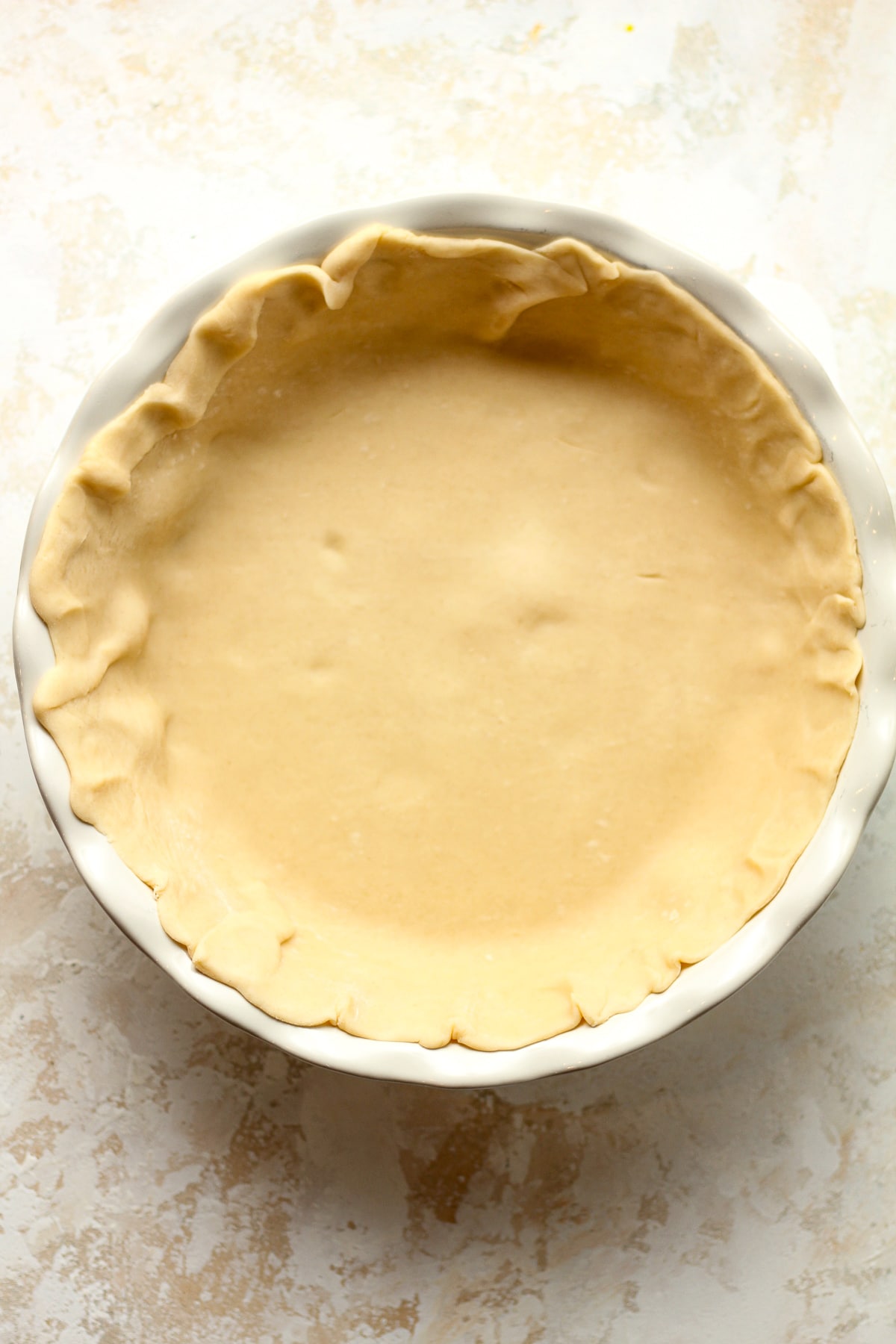 A pie plate with a refrigerated pie crust pressed inside.