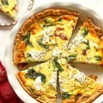 Overhead view of a sliced goat cheese quiche with spinach.