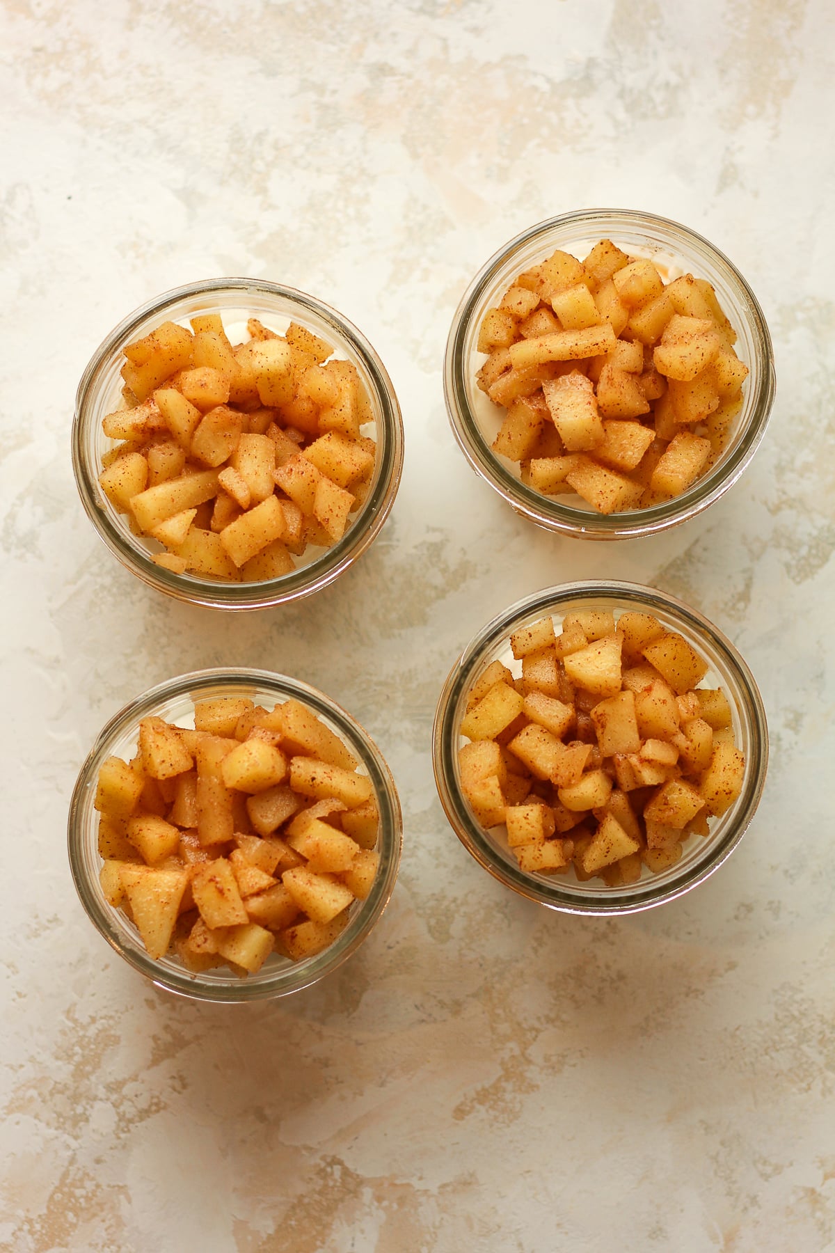 Four mason jars with the cinnamon apples on top.