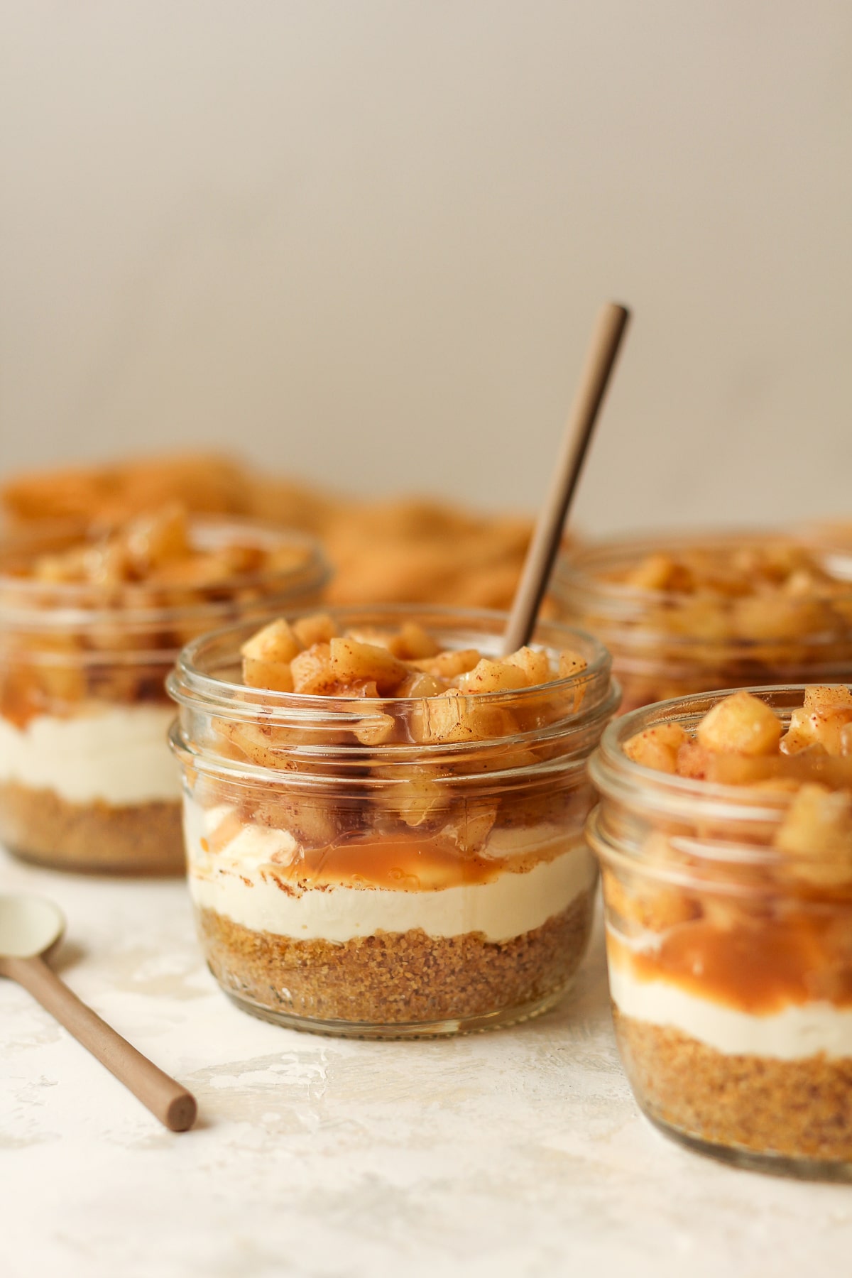 Side view of four mason jars of apple pie with caramel sauce.