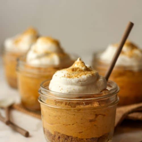 Side view of four mini jars of pumpkin pie with graham crackers.