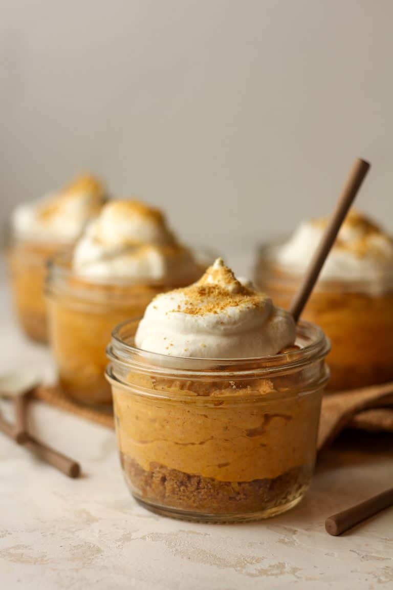 Side view of four mini jars of pumpkin pie with graham crackers.