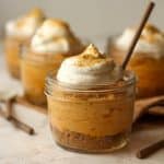 Side view of a jar of pumpkin pie in a jar with a spoon.