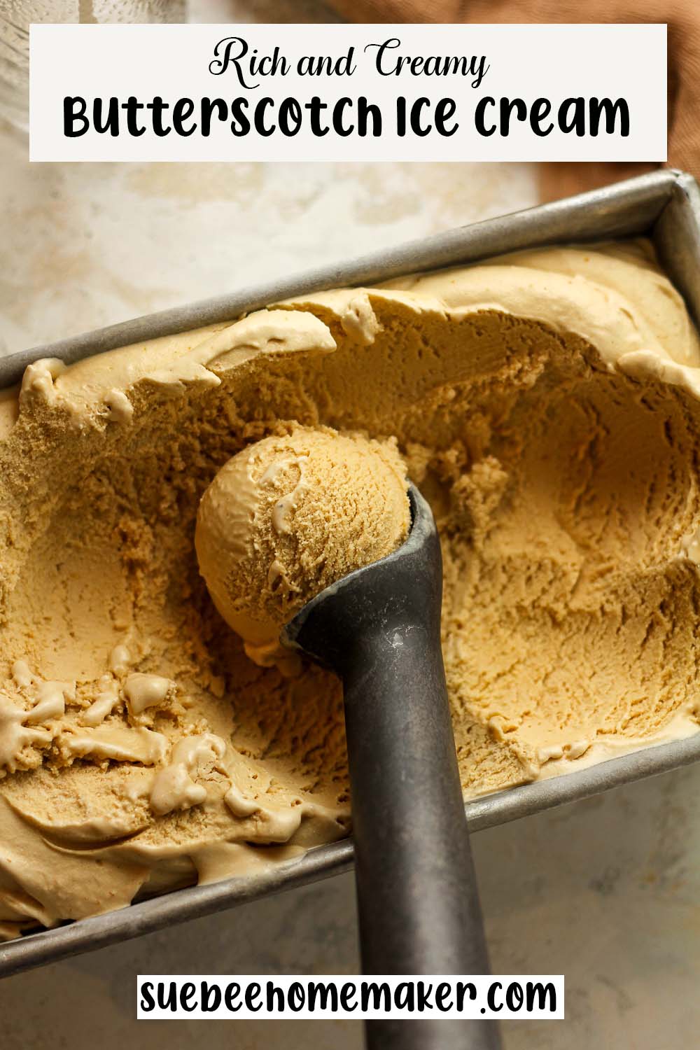 An ice cream scoop inside a loaf pan of butterscotch rich and creamy butterscotch ice cream.