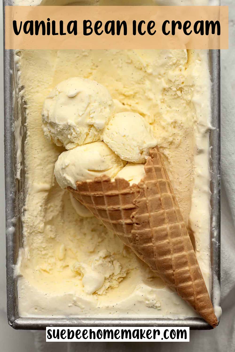 A pan of vanilla bean ice cream with a waffle cone inside.