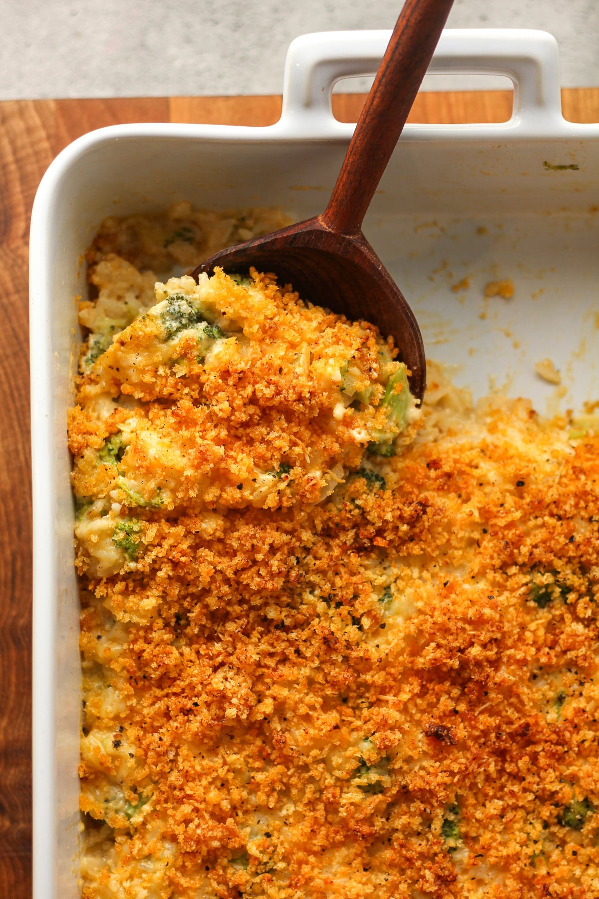 Closeup on the broccoli rice casserole with a wooden spoon digging in.