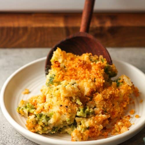 A wooden spoon serving some broccoli rice casserole.