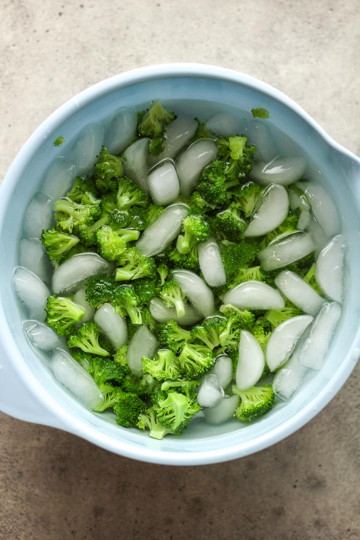 A bowl of the broccoli in ice water.