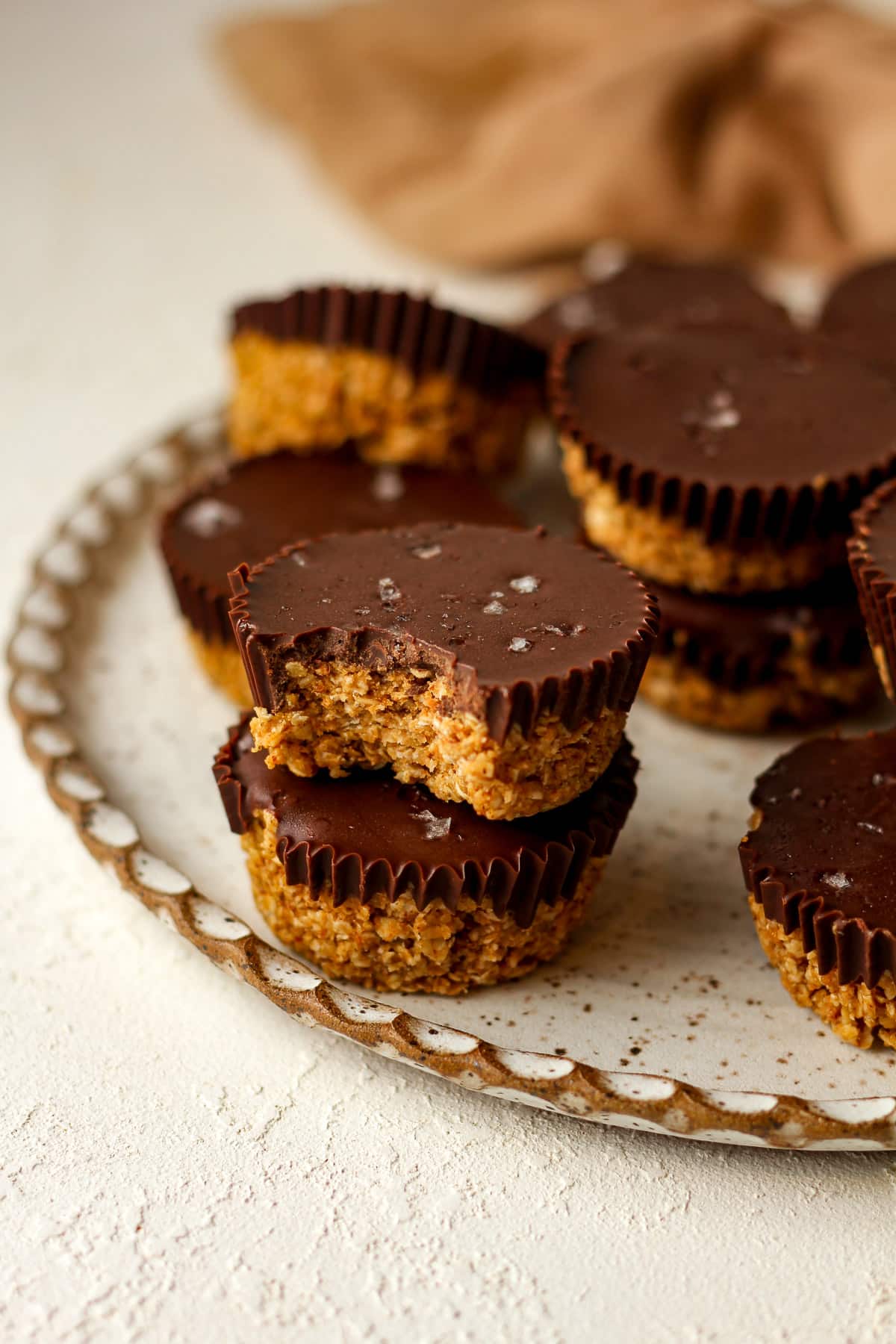 A plate of 12 chocolate peanut butter cups with a bite out of one.