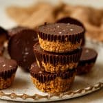 A stack of three chocolate peanut butter oat cups with flaky sea salt.