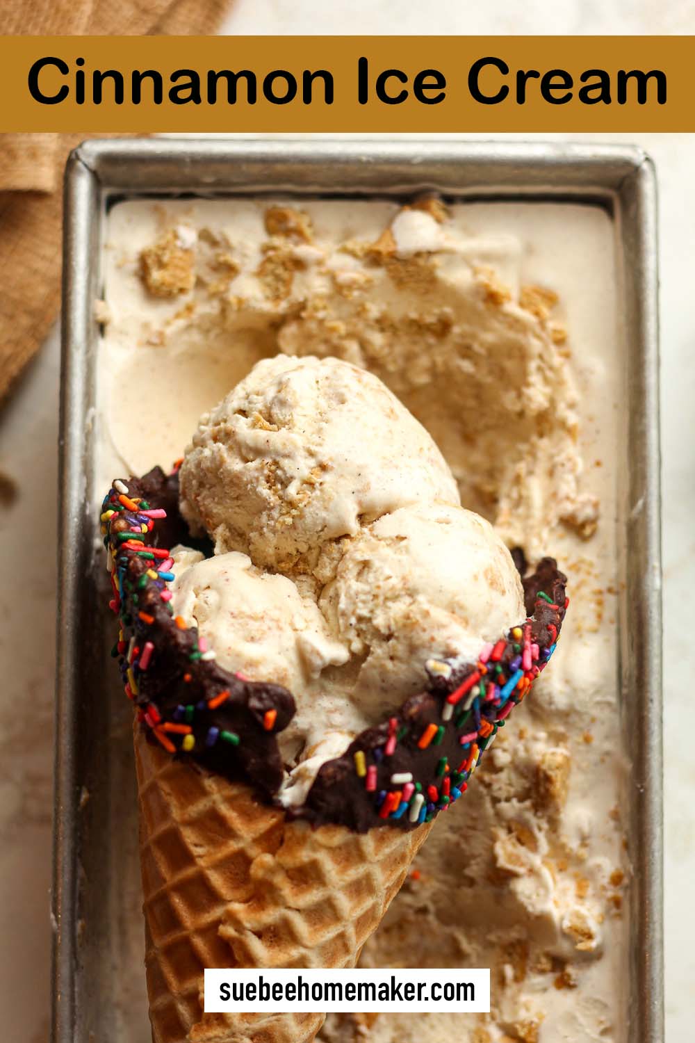 A loaf pan with cinnamon ice cream and a waffle cone of ice cream inside it.