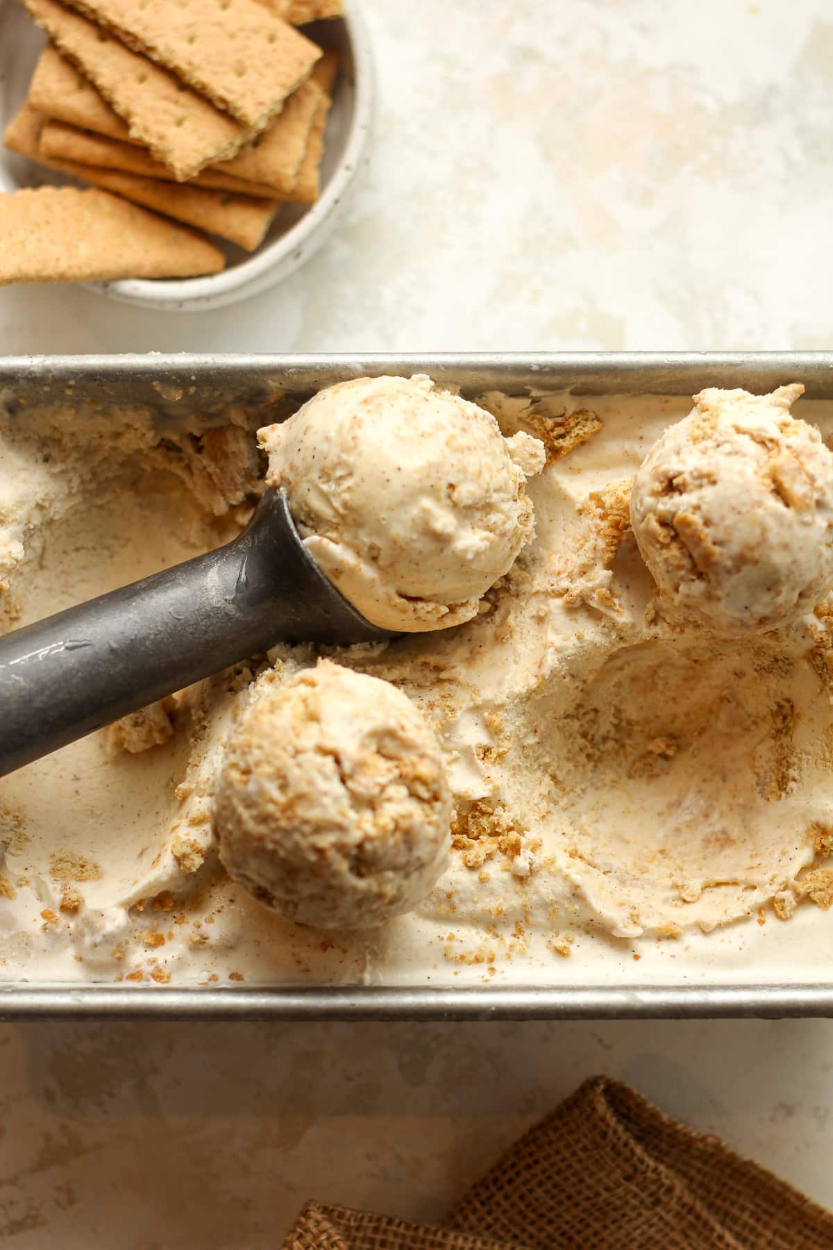 Overhead view of a loaf pan with cinnamon ice cream and an ice cream scoop.