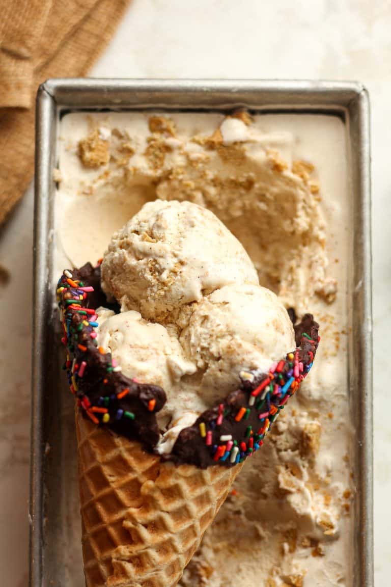 Closeup on a pan of a waffle cone of cinnamon ice cream in a loaf pan of ice cream.