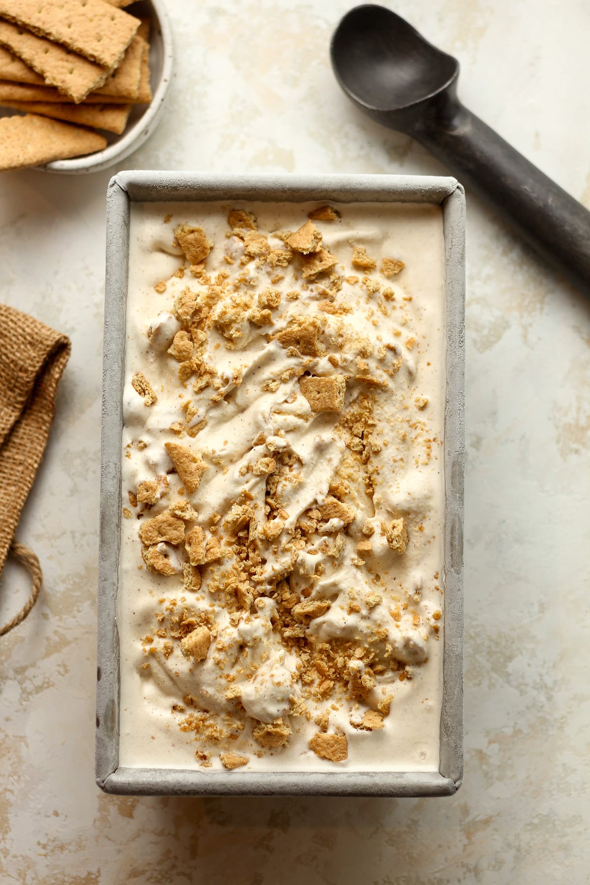 A loaf pan of cinnamon ice cream with crumbled graham crackers.