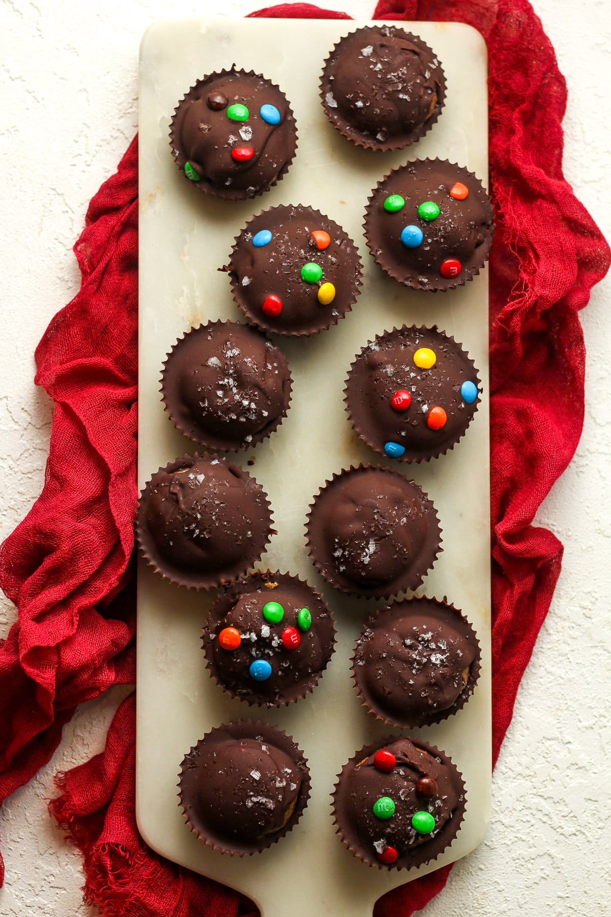 A white tray with 12 peanut butter cups, some with mini m&ms on top.