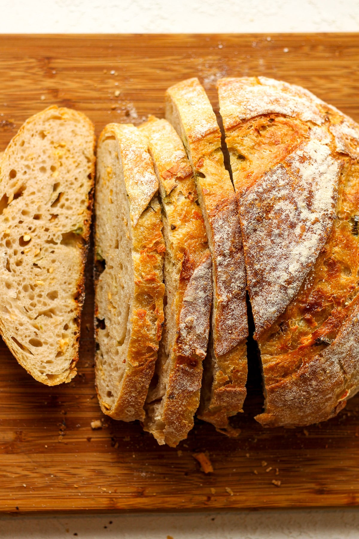 A board of jalapeño cheddar sourdough bread with some sliced.