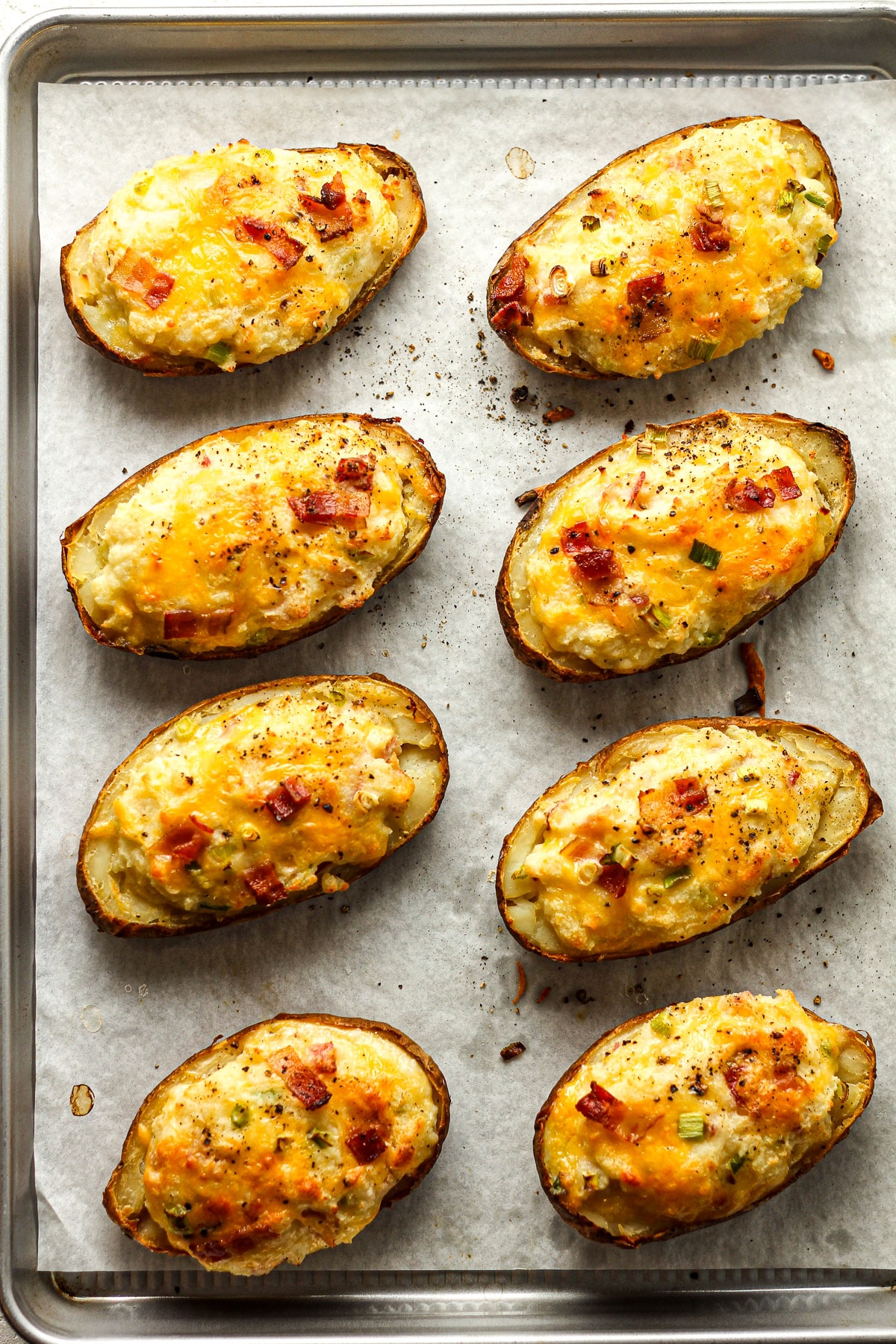 A baking sheet with just baked loaded potatoes.